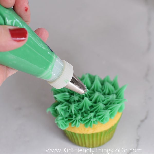 frosting a cupcake with grass frosting
