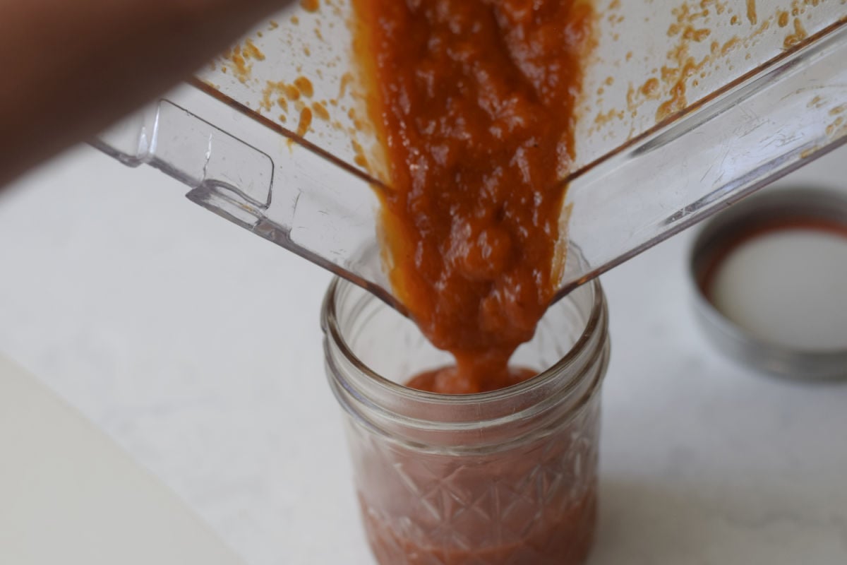 pouring barbecue sauce into jar 