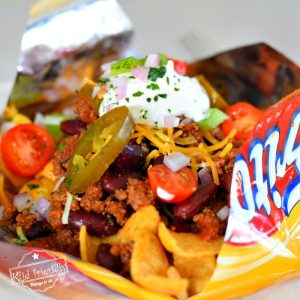 Slow Cooker Frito Pie Recipe with Chili Con Carne - Easy and so delicious. Perfect for game day, tailgating, or family dinner - www.kidfriendlythingstodo.com