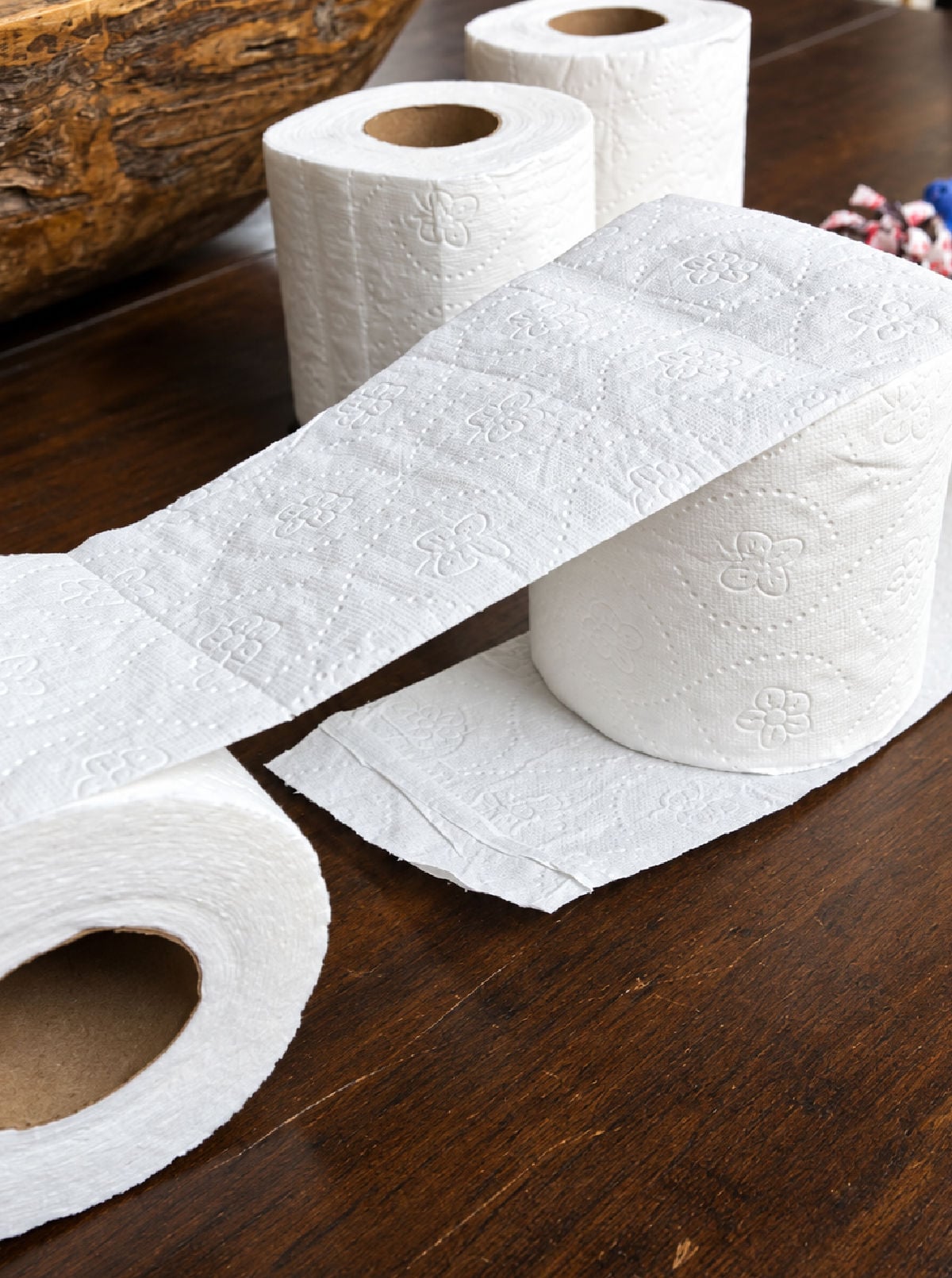 Wrapping toilet paper around a roll to start making the mummy prize ball game.