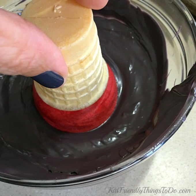 dipping the red candy-coated cake cone in melted black candy melts. 