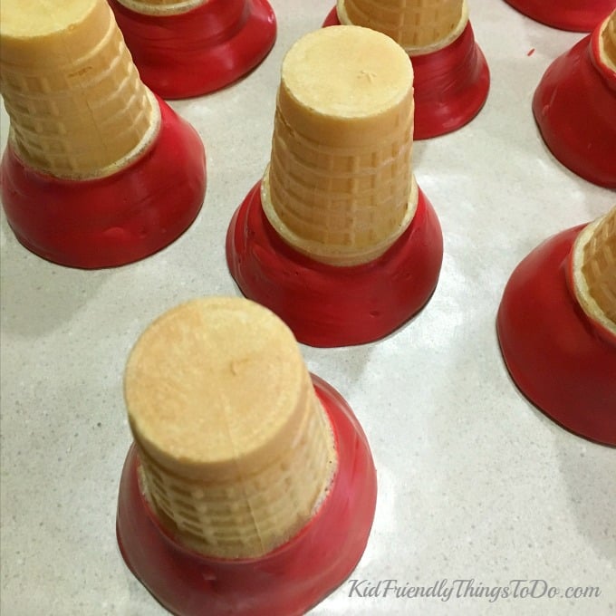 cake cones dipped in red candy melts drying. 
