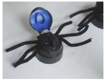 attaching spider legs to coffee lids for spider race game 