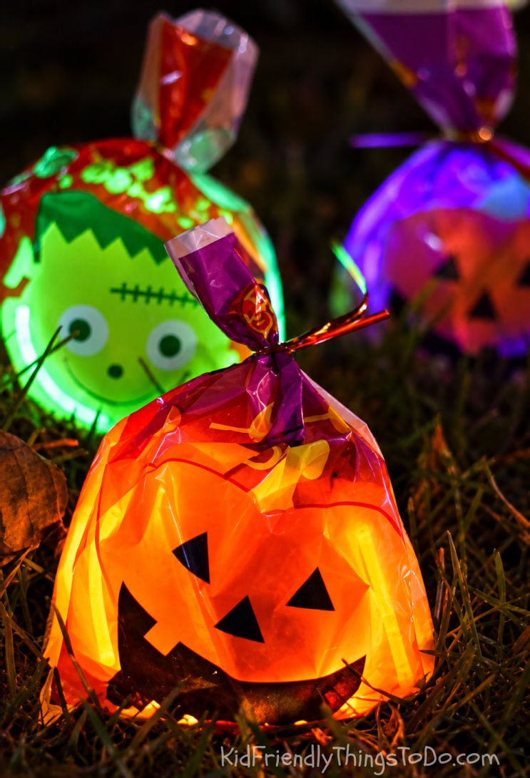 Glowing Halloween treat bags hidden in the grass for a nighttime candy hunt.