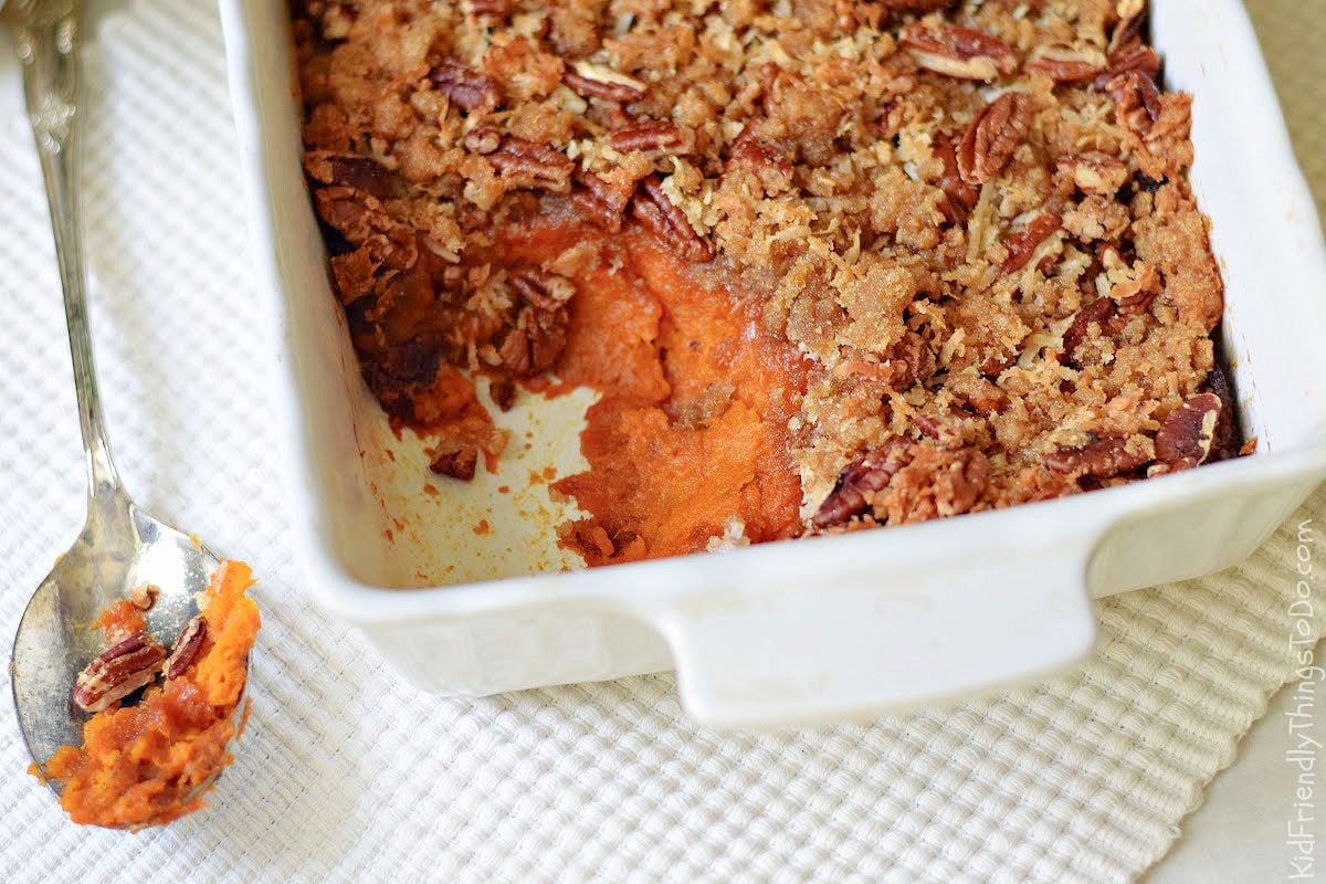sweet potato casserole with scoop out and a coconut pecan crunch topping