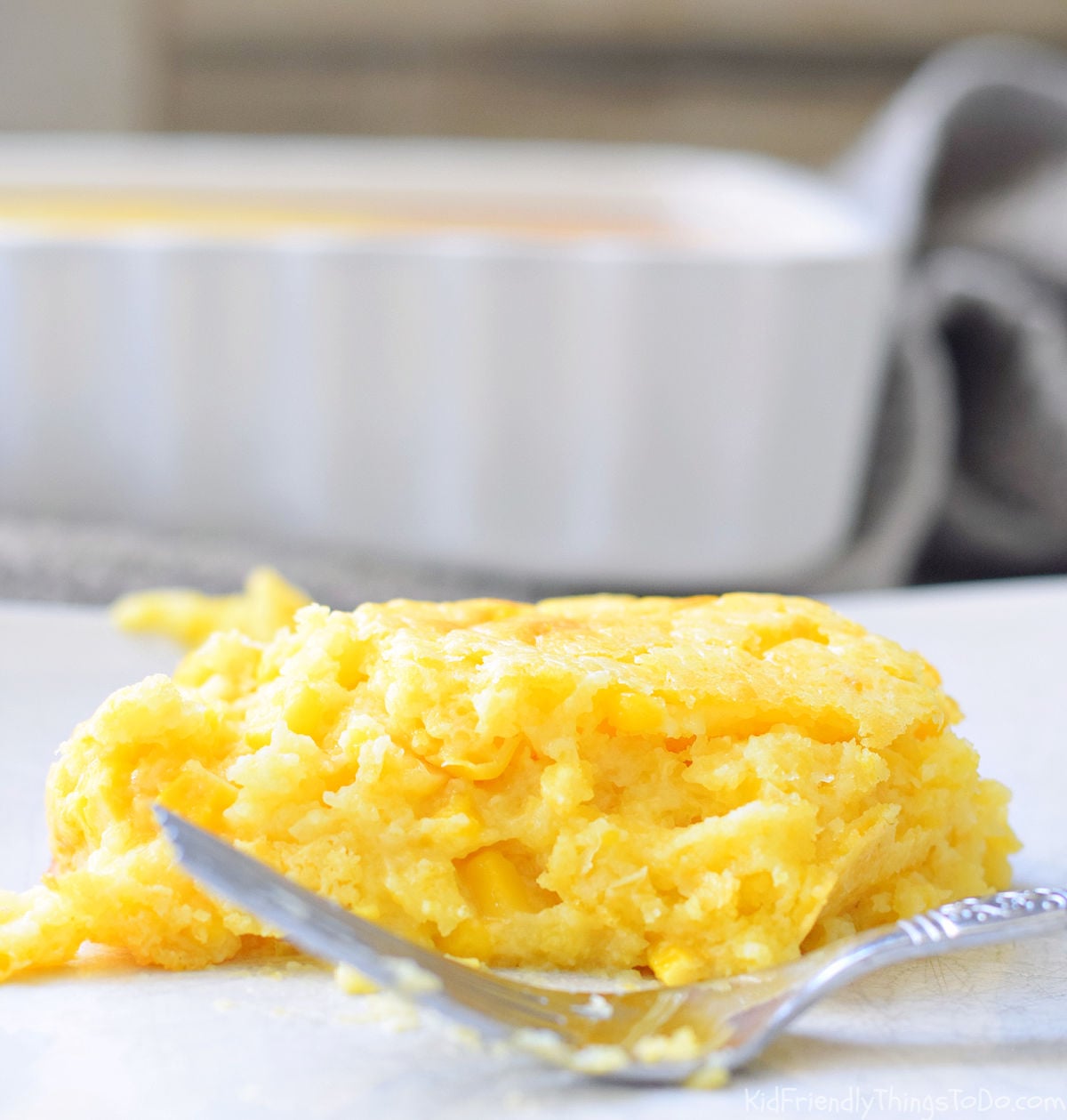 creamy cornbread casserole slice on plate with fork 