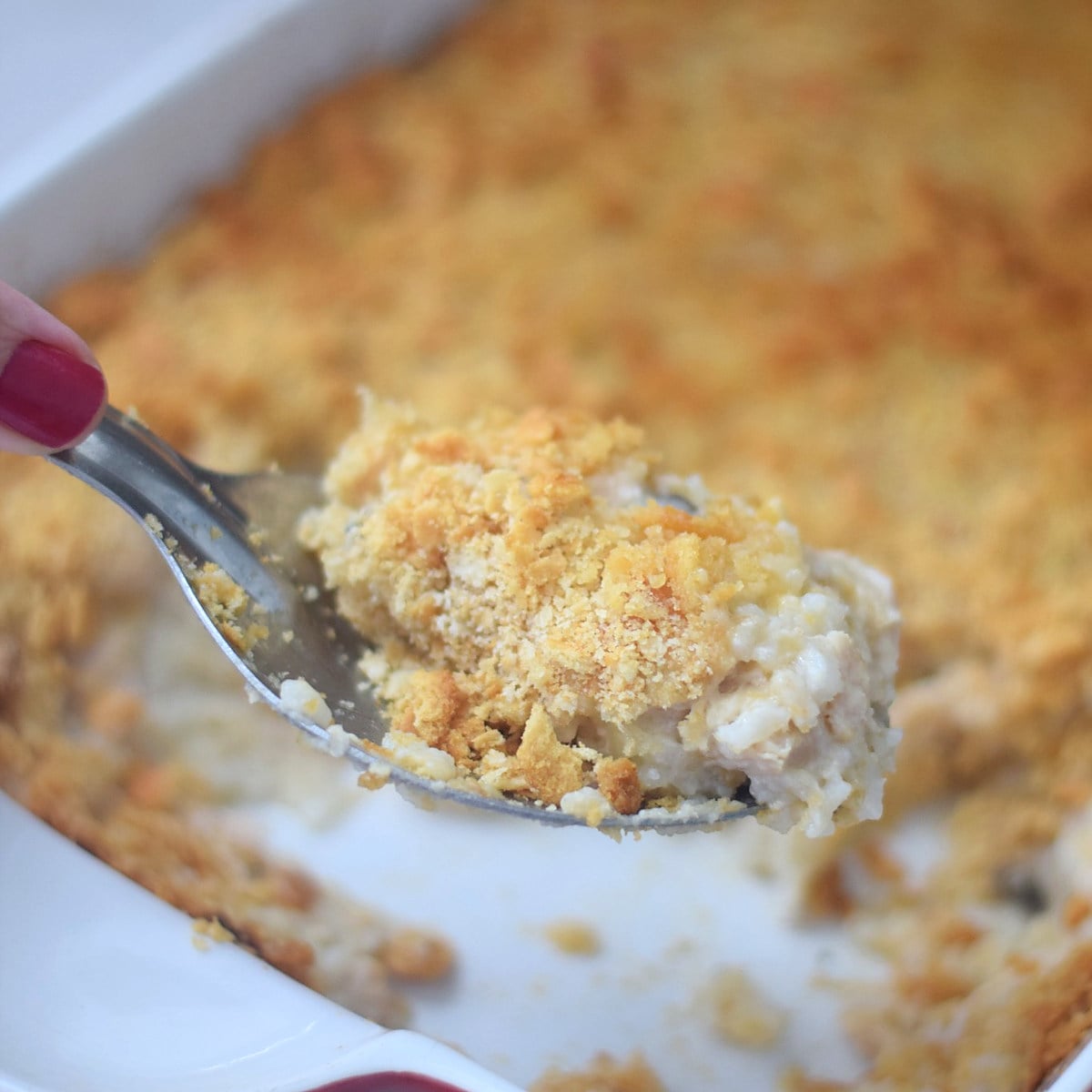 Cheesy chicken and rice casserole with golden Ritz cracker crust on a serving spoon