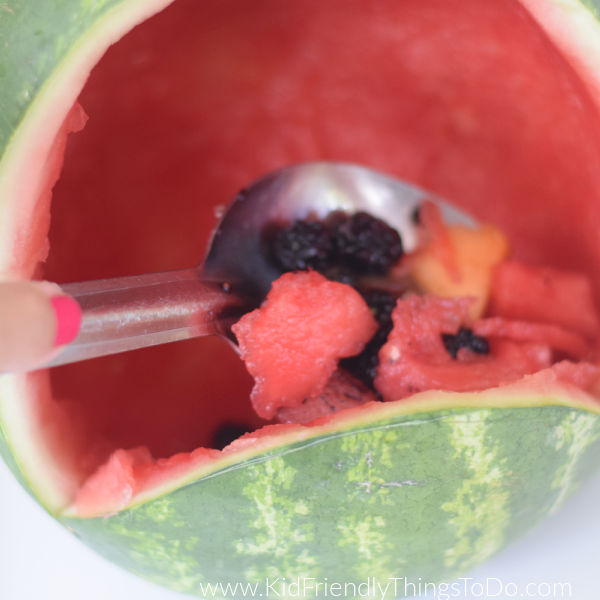 scooping fruit into frog watermelon bowl 