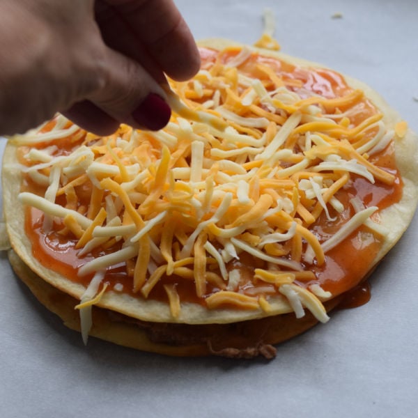 sprinkling cheese on Mexican pizza