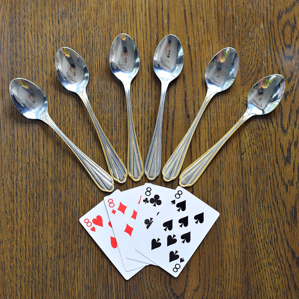Four of a kind with silver spoons arranged for the spoons card game