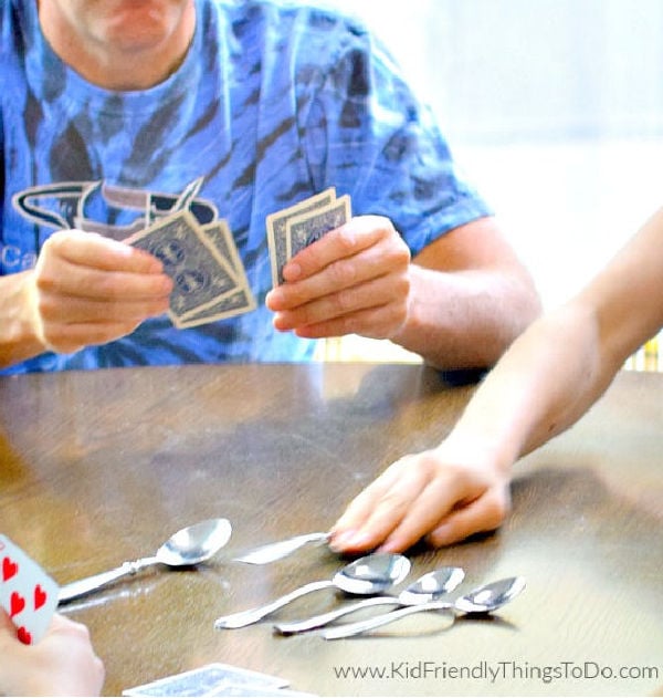 child reaching for spoon in spoons card game
