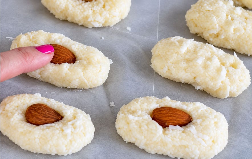 Almond being pressed into a coconut center for homemade Almond Joy bars