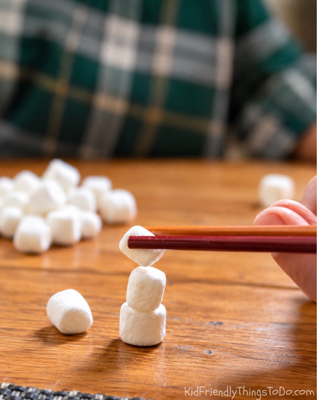 Stacking mini marshmallows with chopsticks for a challenging Snowman Stack Minute to Win It game.