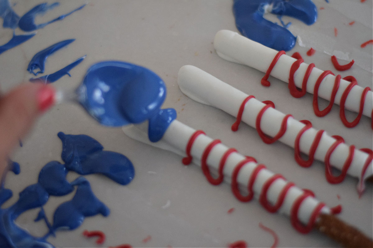 spooning chocolate onto patriotic pretzels