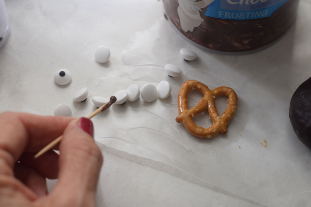 adding chocolate frosting to candy eyes 