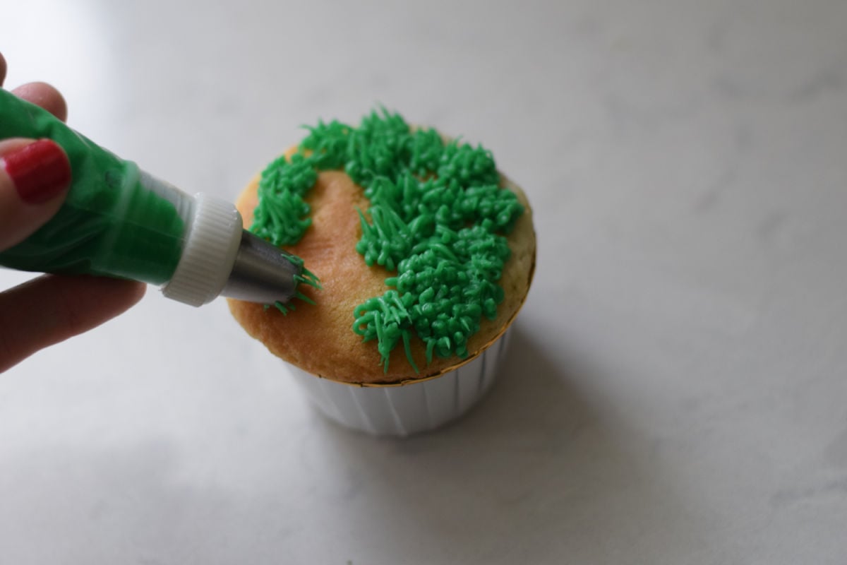 piping green frosting with grass tip