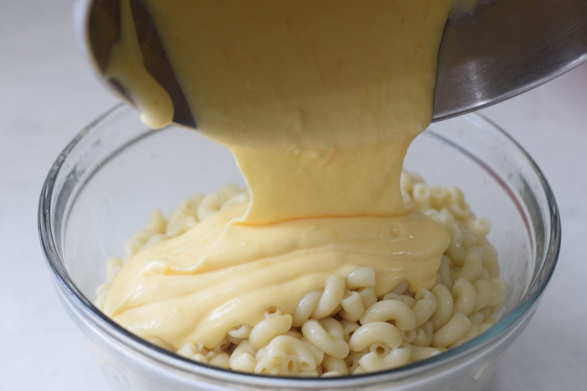 pouring cheese over macaroni noodles