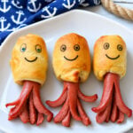 Octopus hot dogs made with crescent roll dough and hot dogs with edible marker smiles on a white plate