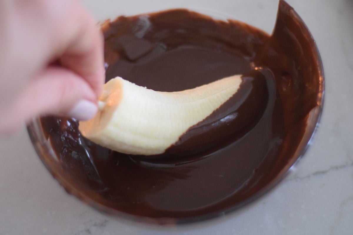 dipping banana pops into chocolate