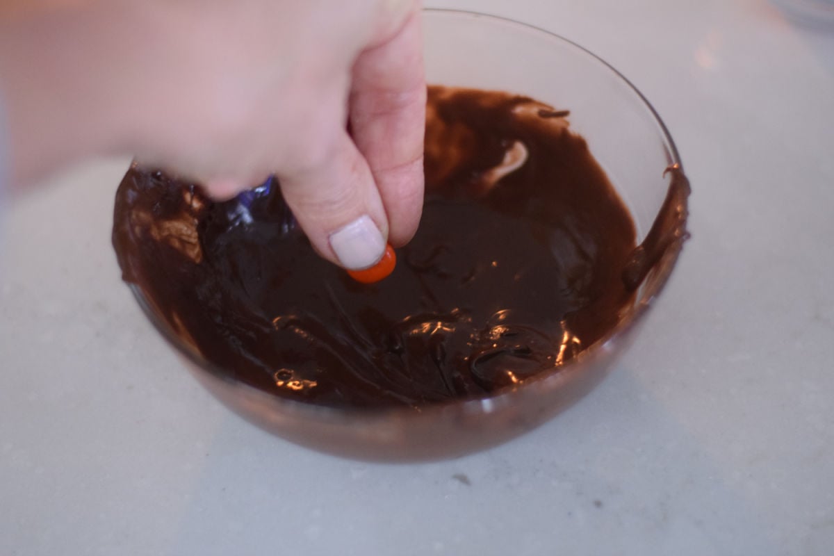 dipping M&M into chocolate