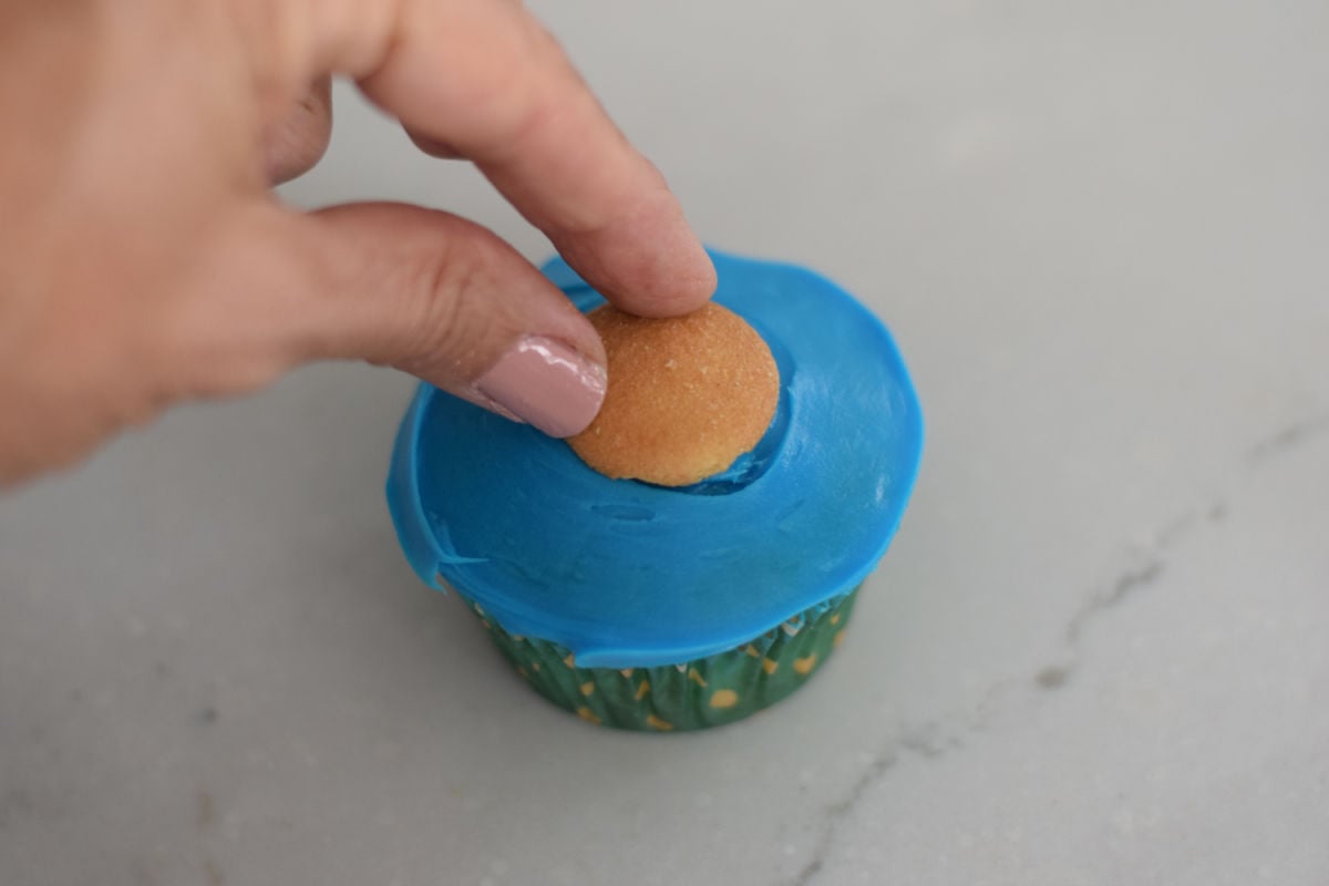 placing vanilla wafer on cupcake