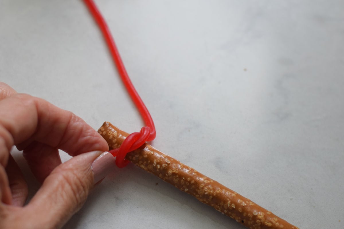 tying licorice around pretzel rod 