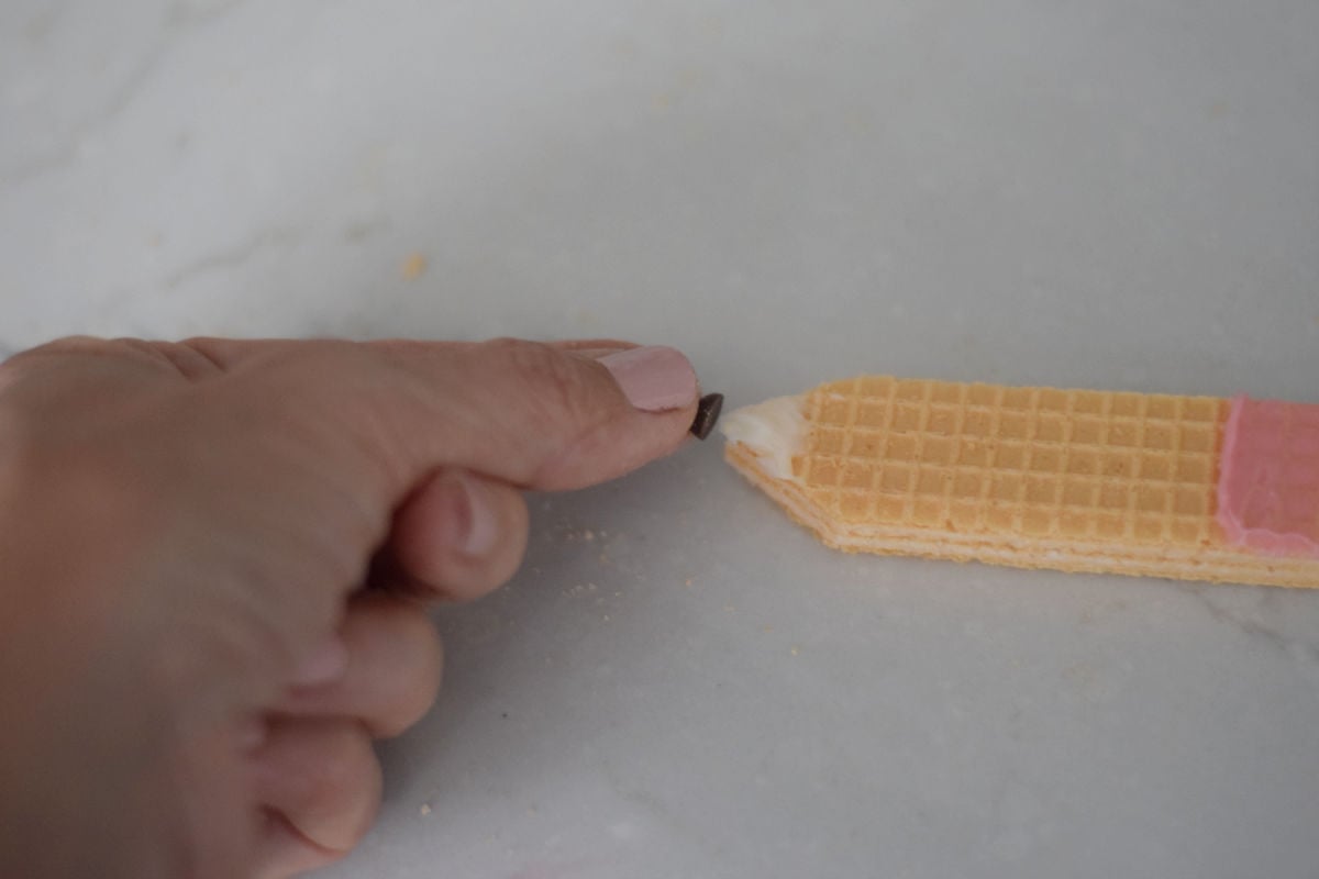 pushing chocolate chip onto pencil cookie 