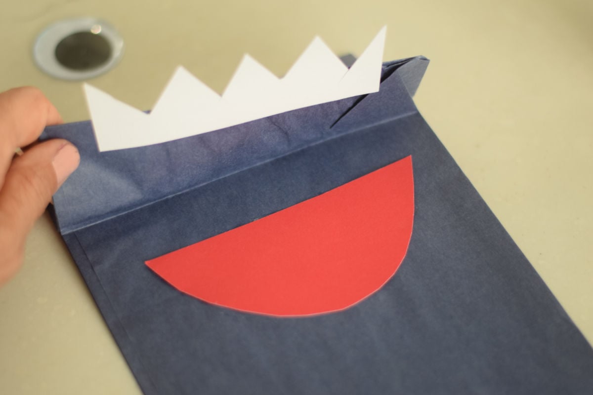 gluing mouth and teeth on shark paper bag craft 