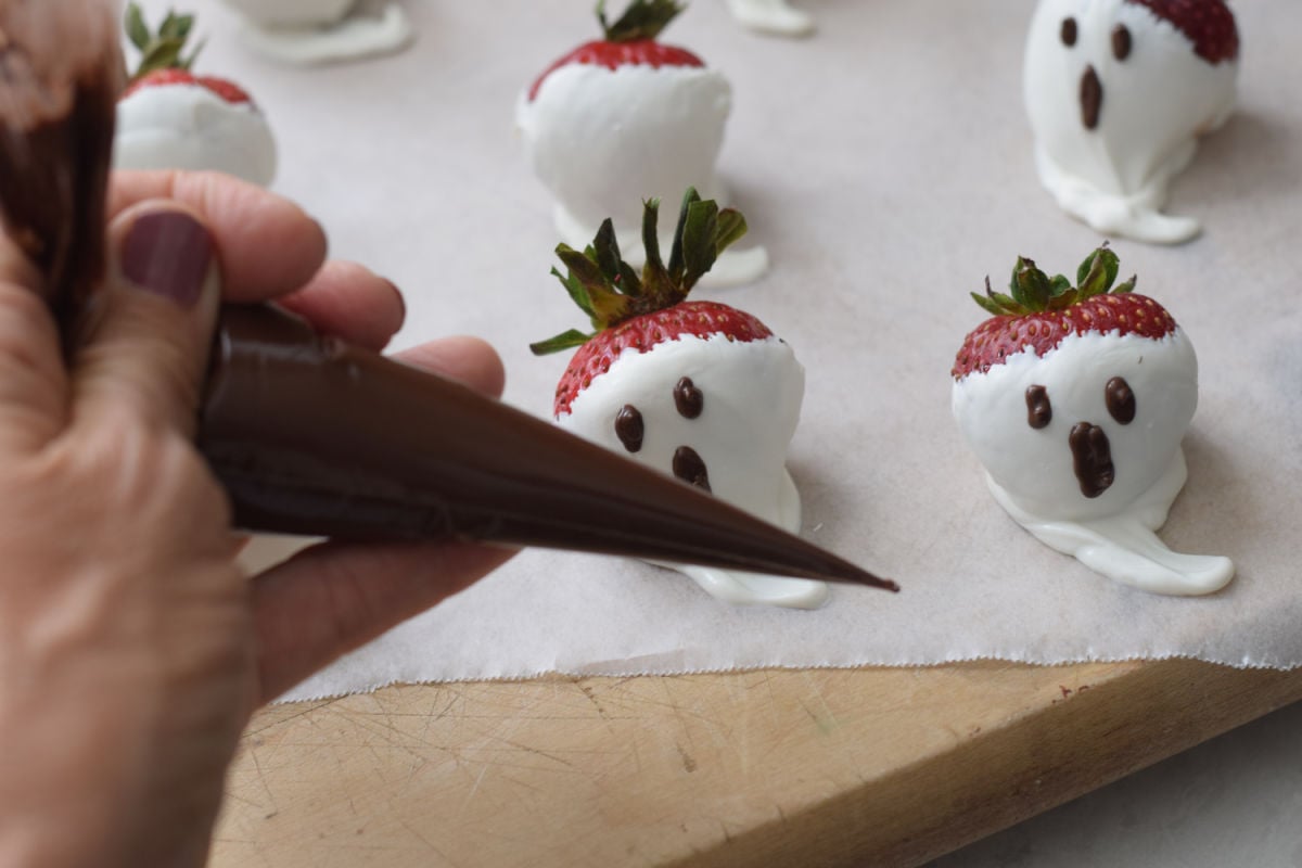 piping ghost face on strawberries 