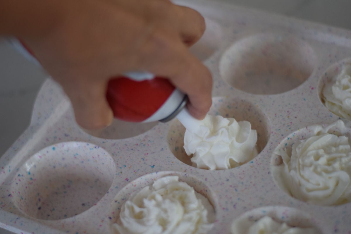 squeezing whipped cream into muffin tin