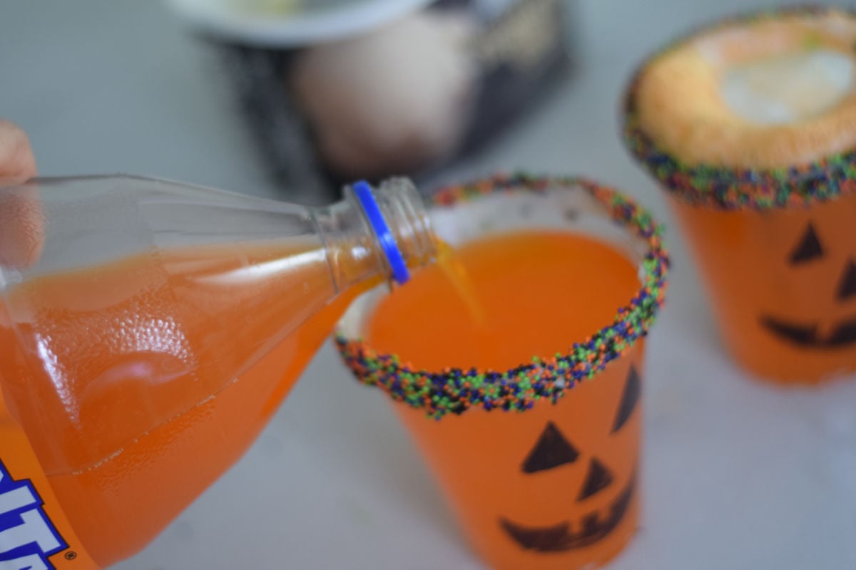 pouring soda into a Jack-O-Lantern cup 