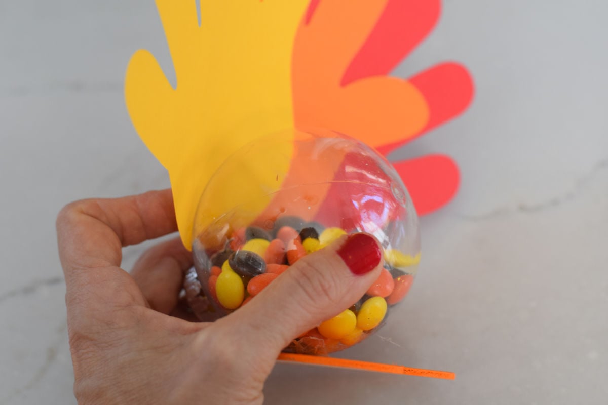 gluing handprint feathers onto plastic ornaments 