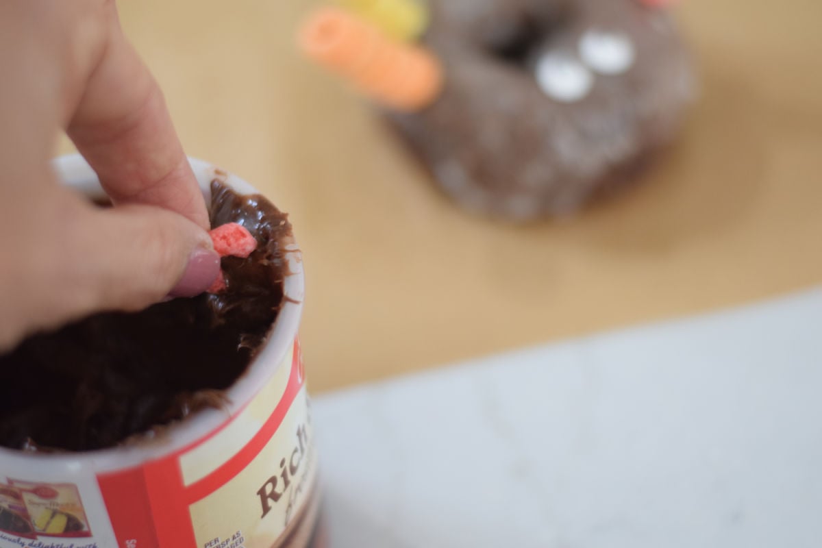 adding chocolate frosting to fruit loops