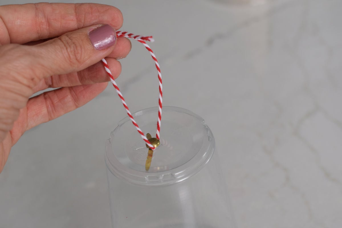 adding a brad and twine to a cup for hanging