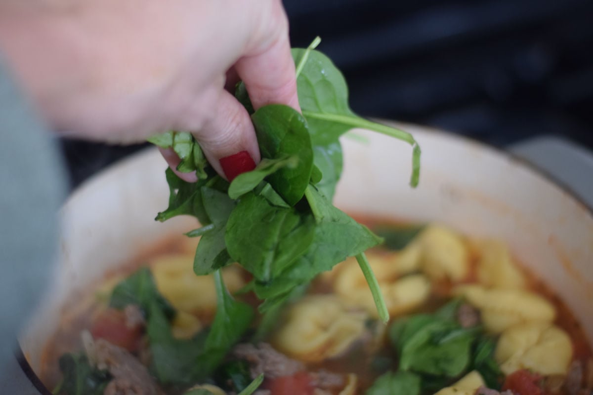 adding spinach to sausage soup