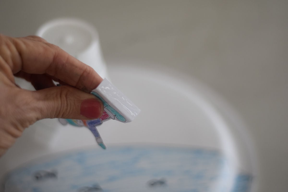 gluing kid to igloo paper plate craft 