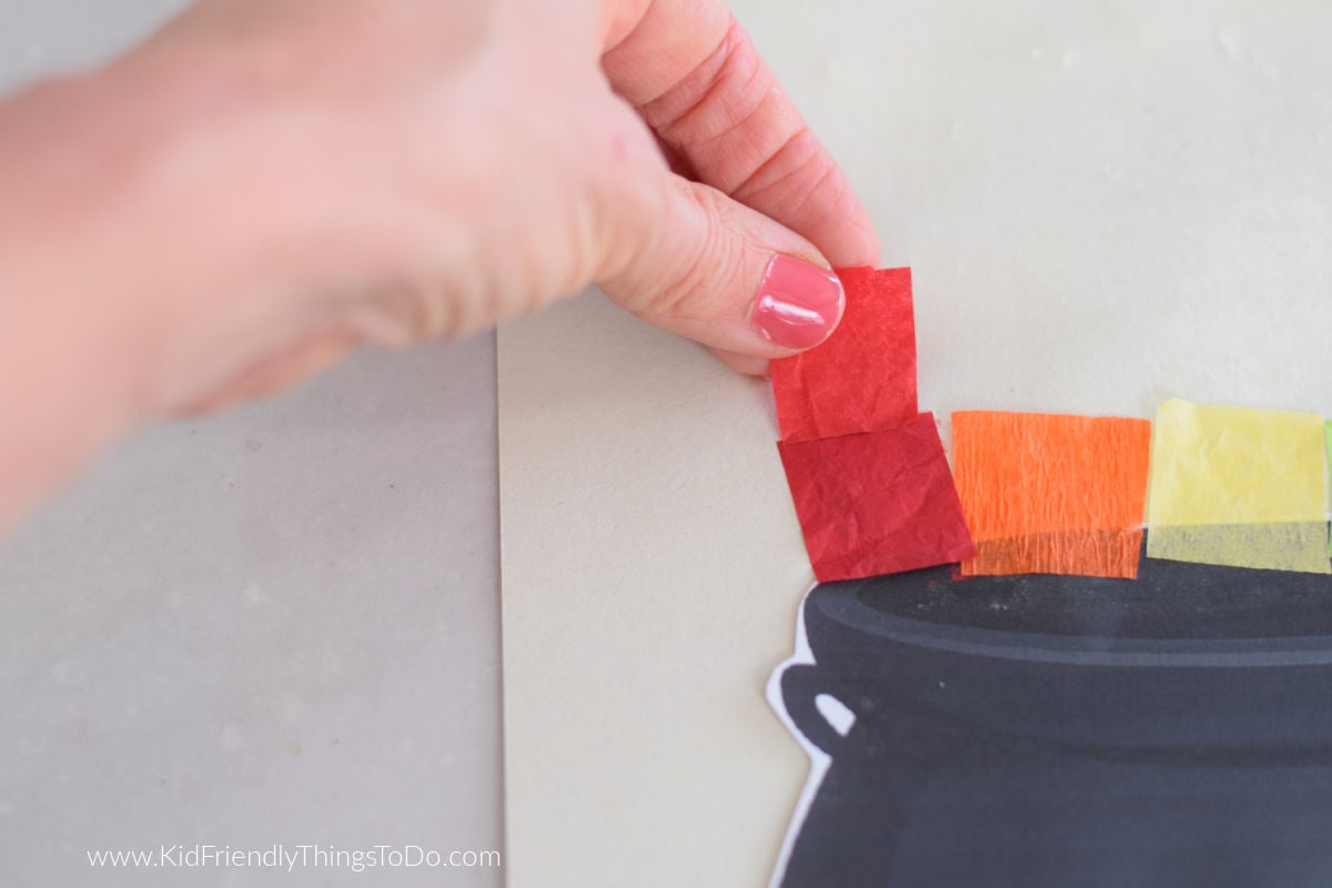 adding tissue paper rainbow to cauldron