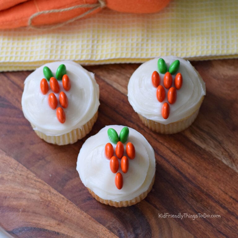 Carrot cupcakes decorated with white frosting and orange and green M&Ms for an easy Easter treat idea