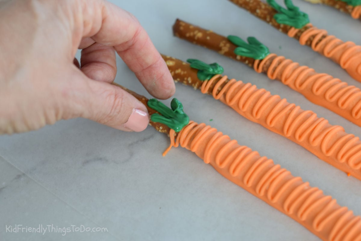 adding chocolate leaves to orange carrot pretzels 