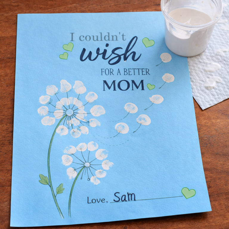 Kids fingerprint dandelion craft for Mother’s Day with white paint on blue paper