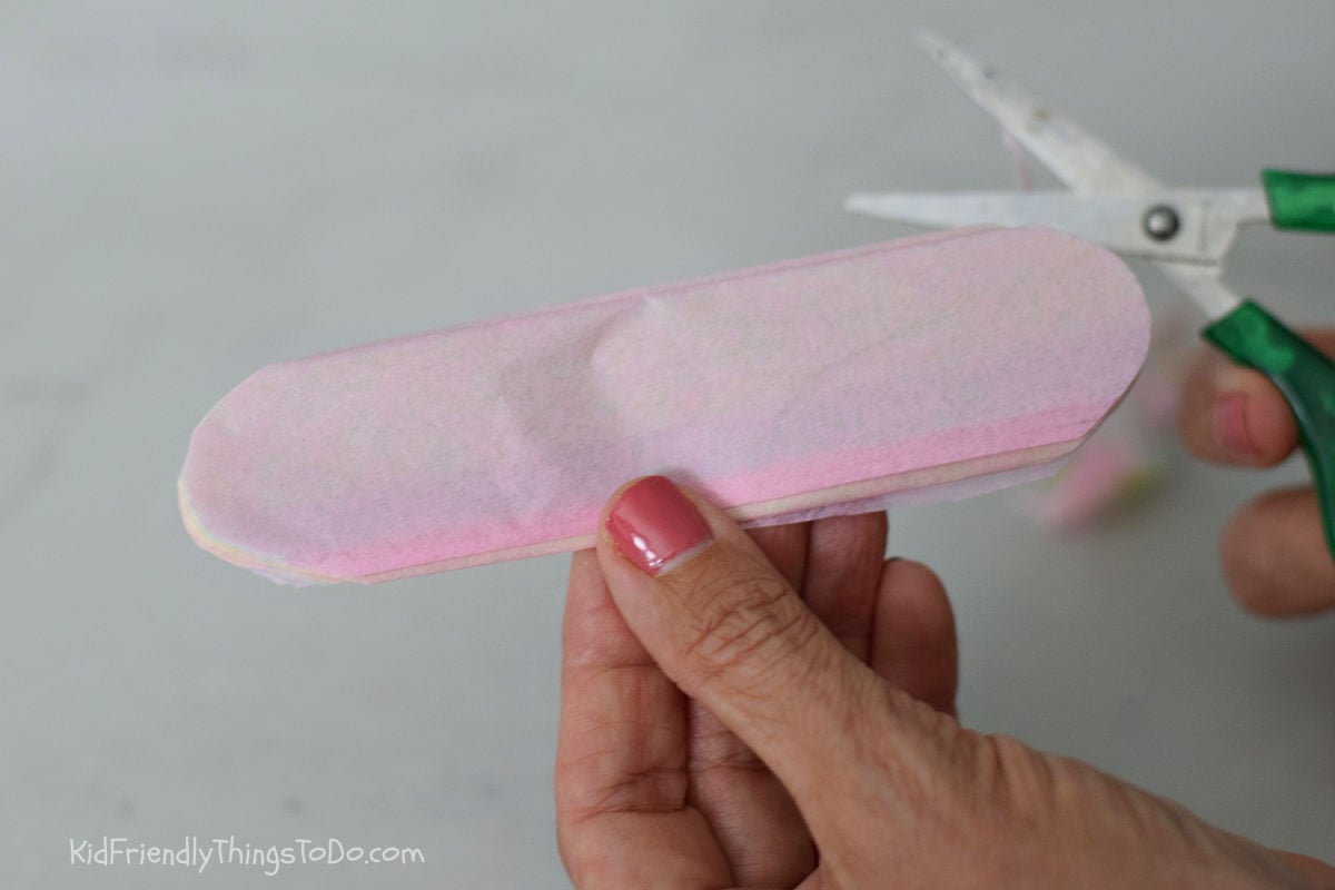 cutting rounded edge of tissue paper flowers to make scalloped edges 