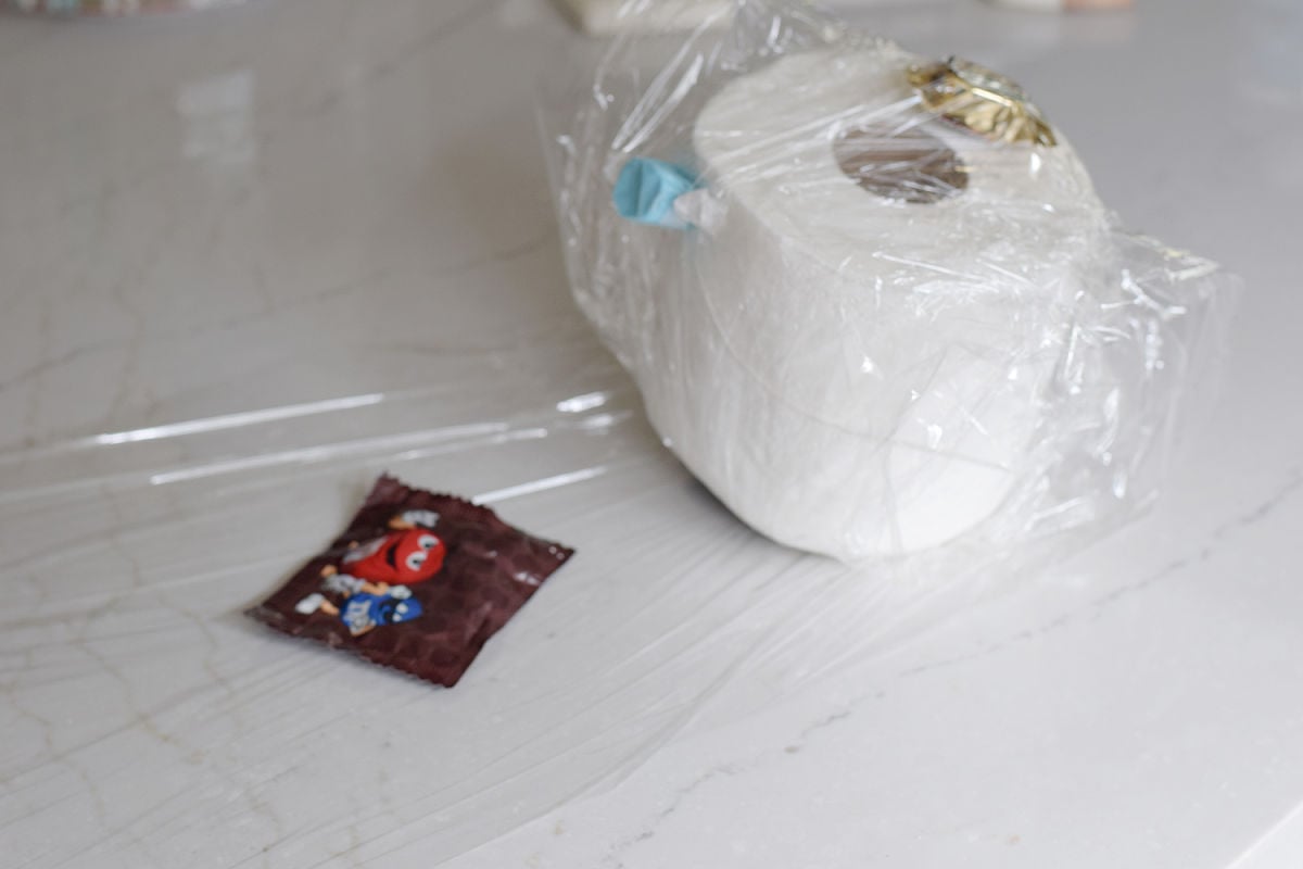 Small bag of M&M’s placed on plastic wrap beside the partly wrapped prize ball.