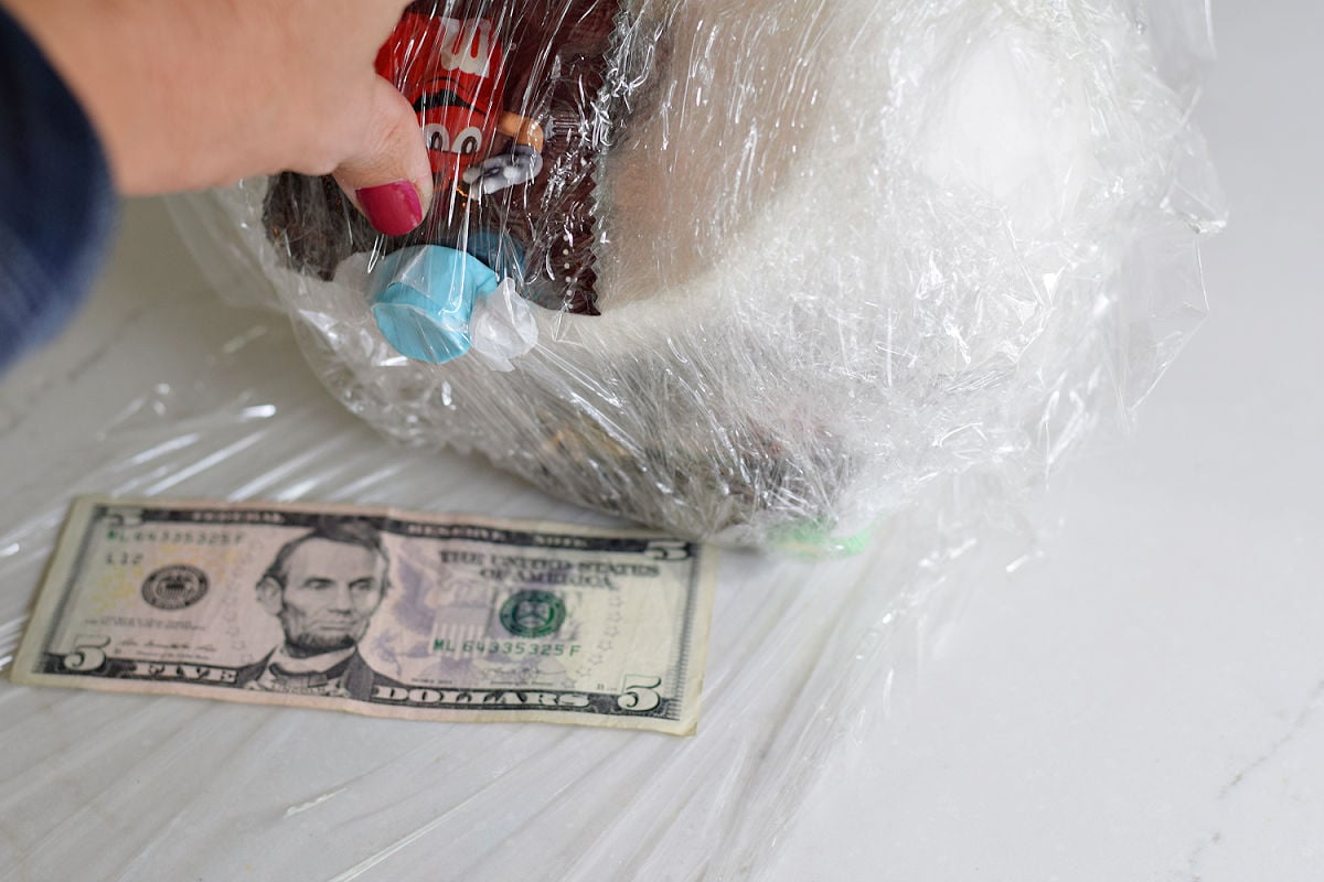 Adding a five-dollar bill between plastic-wrap layers of the saran wrap game ball.