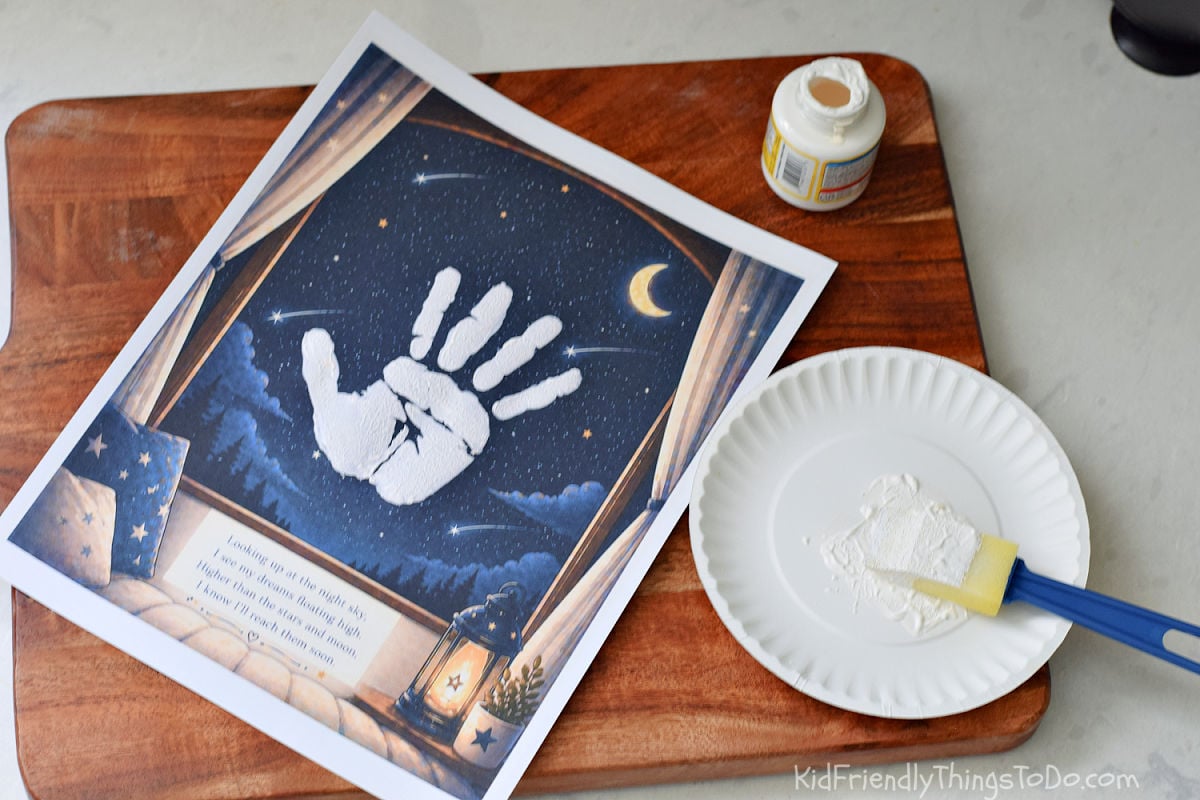 Kids handprint art printable in progress with white paint and sponge on night sky background