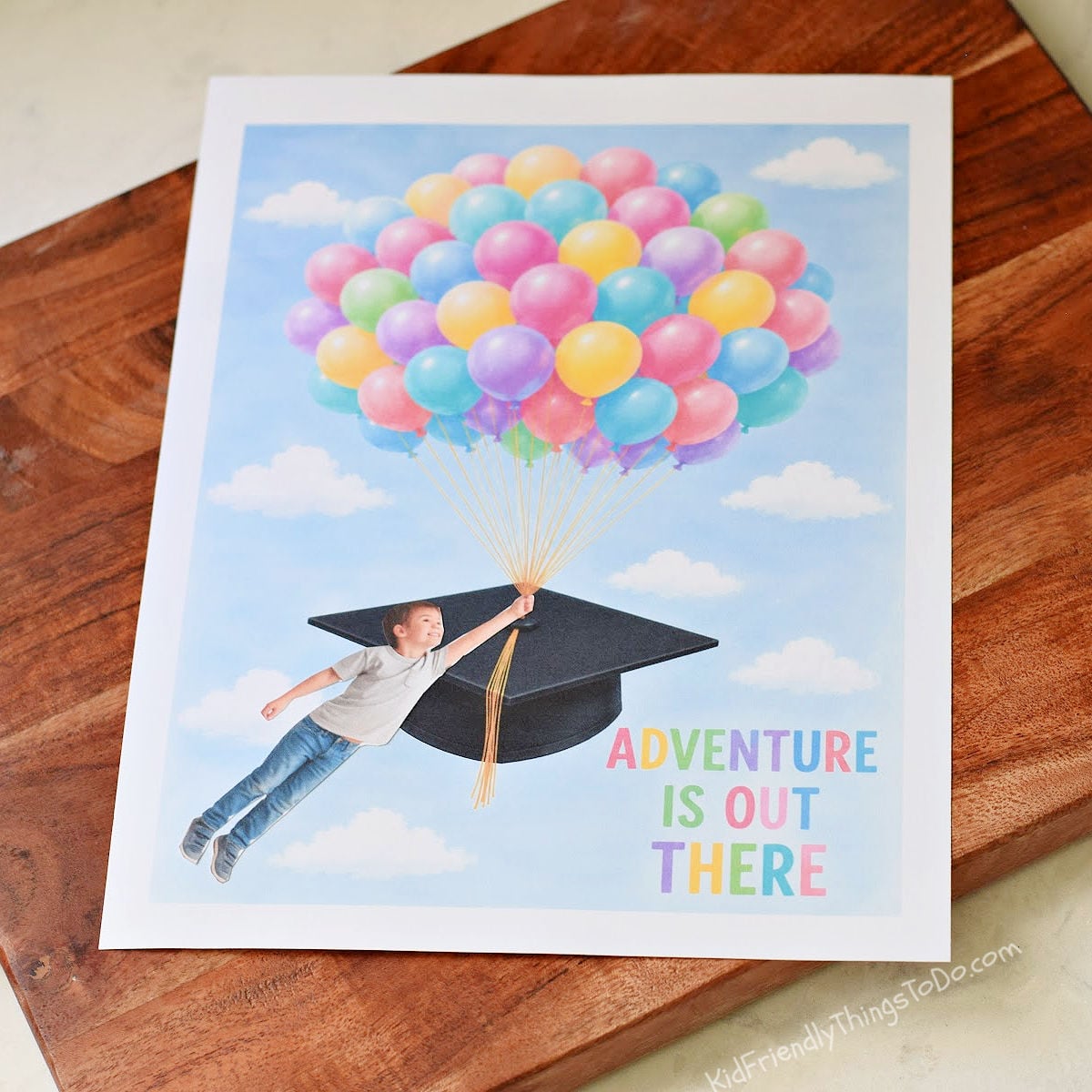Child graduation keepsake craft with colorful balloons lifting a graduation cap while a cut-out photo of a child appears to fly through the sky holding the balloon strings.