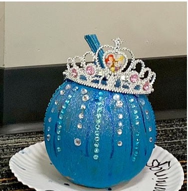 Turquoise Ariel pumpkin decorated with glitter, vertical rows of gems, and a silver tiara with pink jewels.
