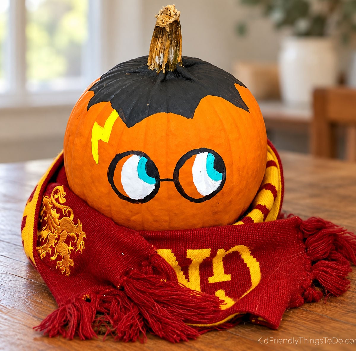 Harry Potter pumpkin with painted black hair, round glasses, a yellow lightning bolt scar, and a red-and-gold Gryffindor scarf.