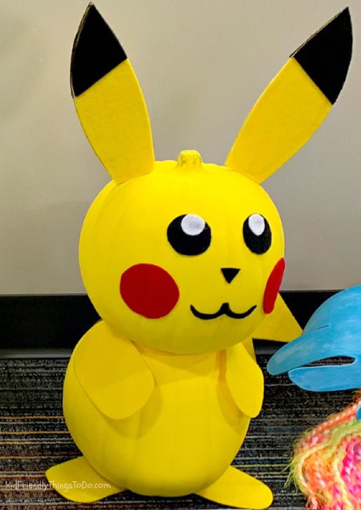 No-carve Pikachu made from two stacked yellow pumpkins with black-tipped ears, red cheeks, and yellow arms and feet.