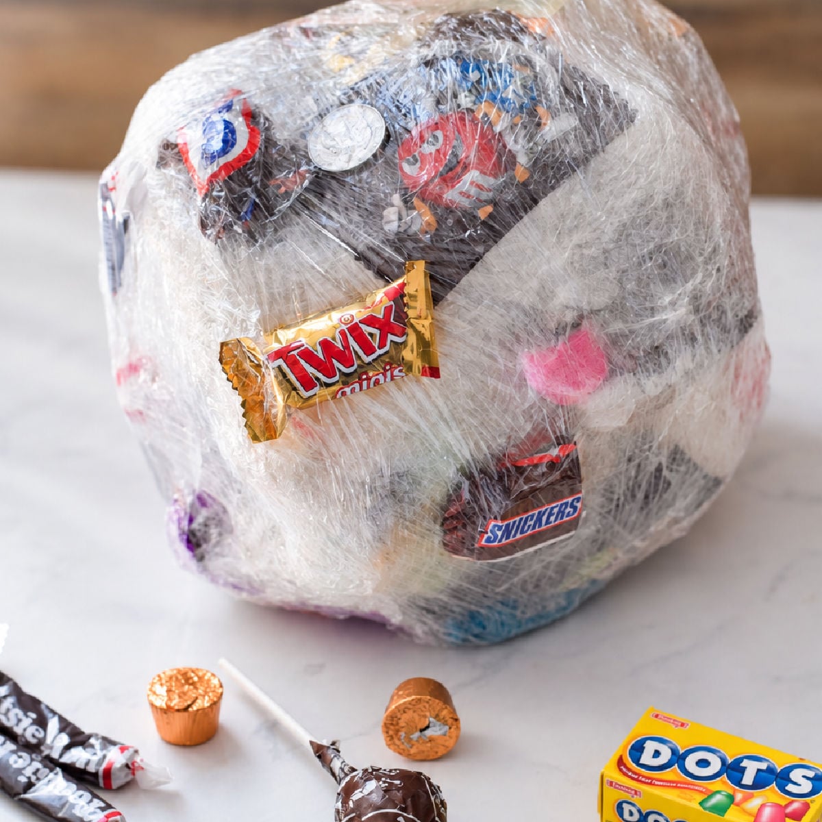 Saran wrap ball game filled with candy and coins, with wrapped treats and a five-dollar bill on the table.