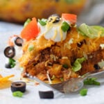 Dorito Casserole centered on plate with sour cream and other toppings